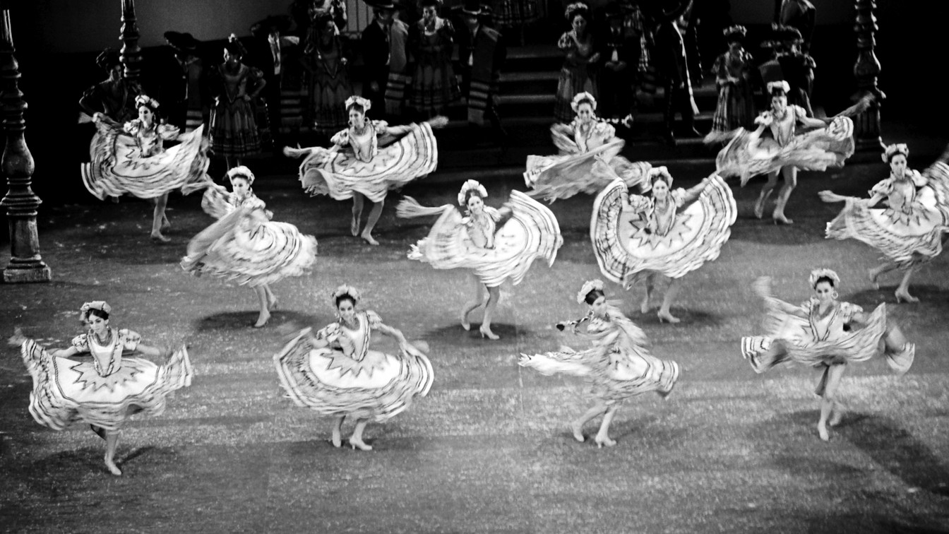 Ballet Folklórico de México tour stage: empty theater with red curtain and amber light