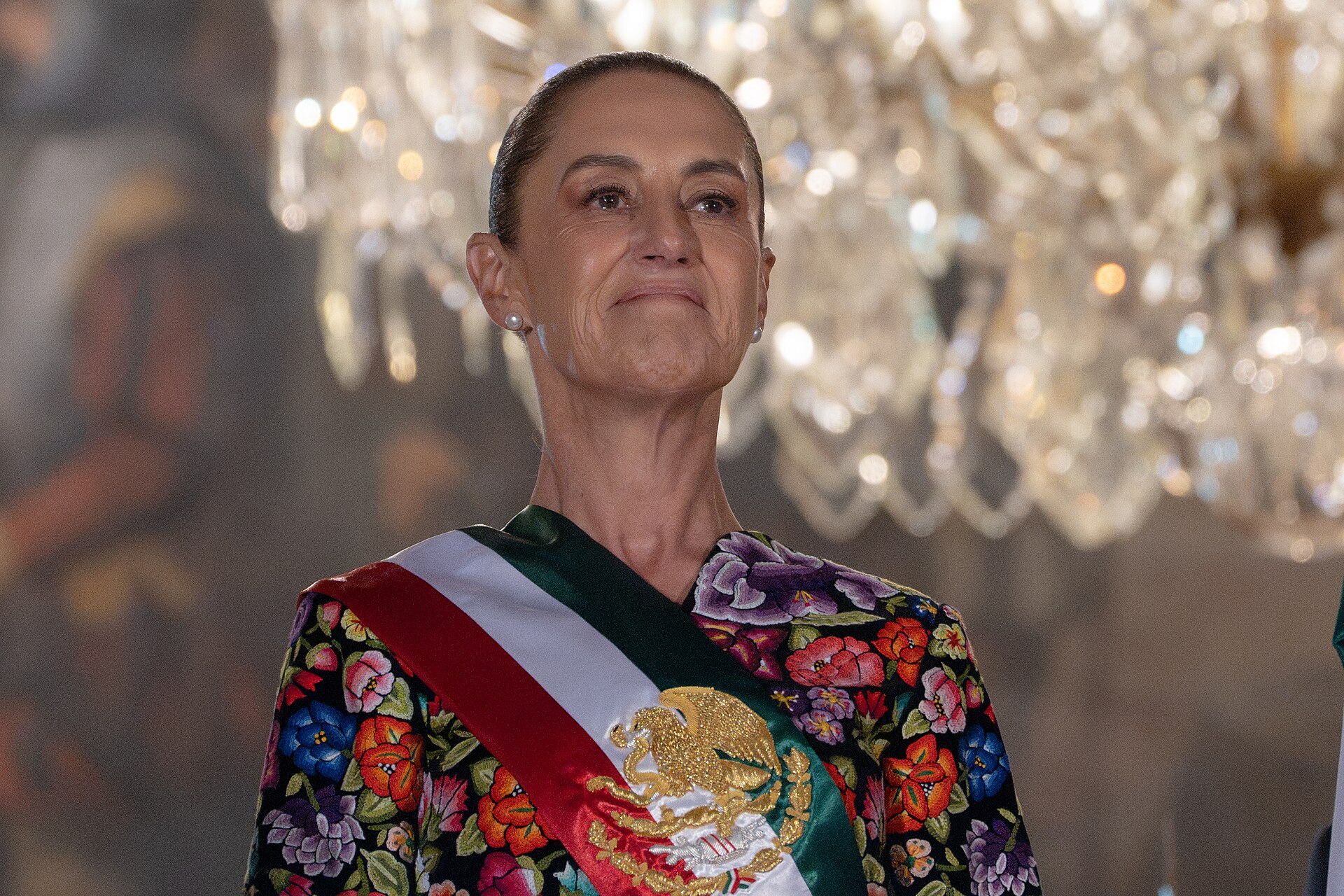 President Claudia Sheinbaum, wearing the presidential sash and a blouse embroidered with flowers, on the balcony of the National Palace during the 2026 Independence Day Grito.