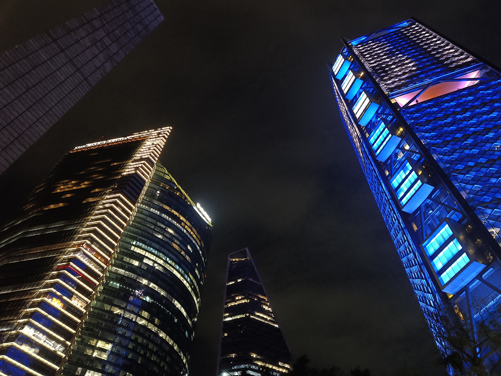 Illuminated skyscrapers along Paseo de la Reforma in Mexico City, seen from below at night.